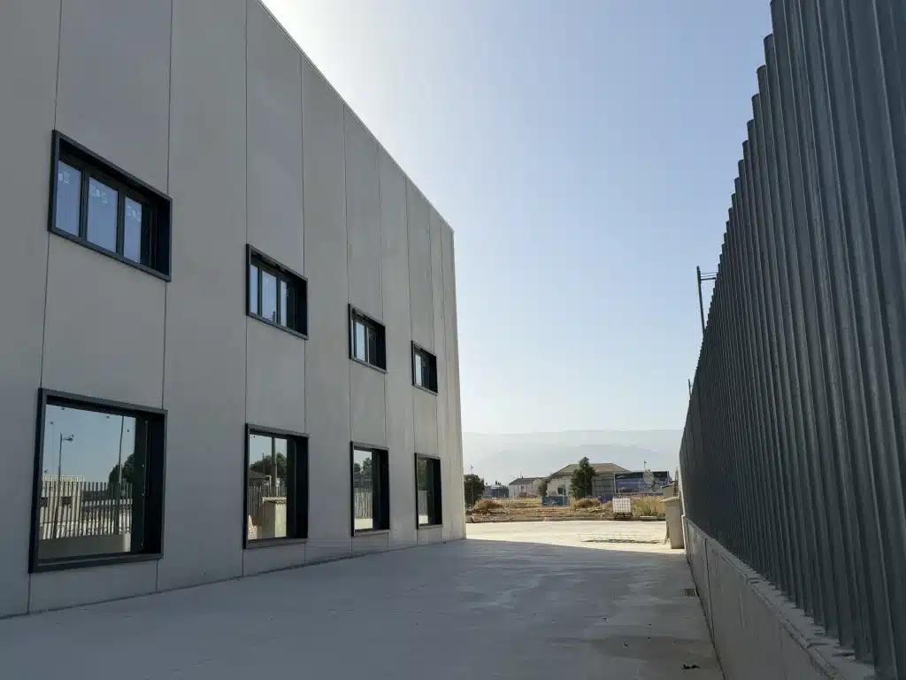 Celosía de lamas verticales de hormigón prefabricado en fachada de nave industrial — Los Cahices, Granada