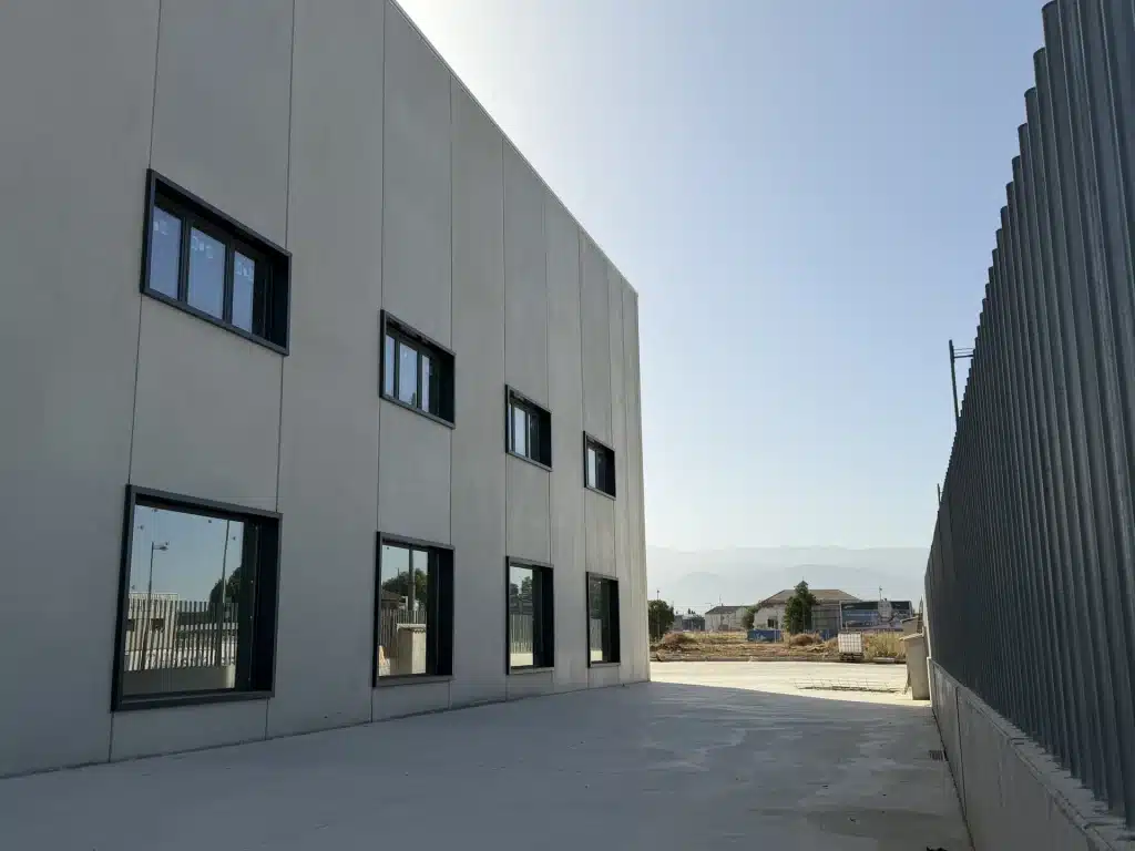 Celosía de lamas verticales de hormigón prefabricado en fachada de nave industrial — Los Cahices, Granada